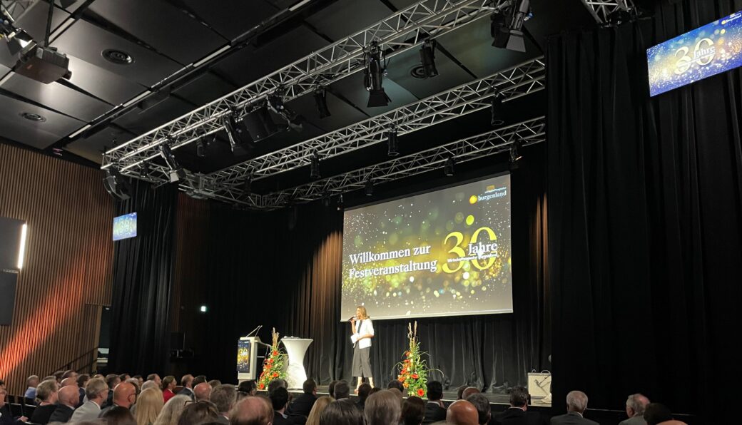 Festveranstaltung mit Bühne, Redner und Publikum, Willkommen zur Jubiläumsveranstaltung 30 Jahre, Bühnenaufbau mit Trussing und Beleuchtung
