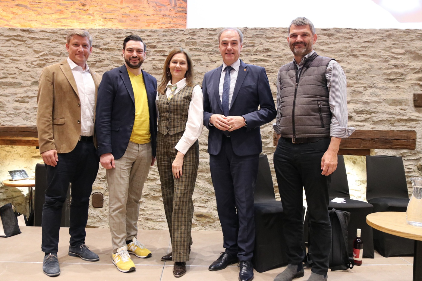 Neun Personen stehen nebeneinander im Granarium der Burg Schlaining. Zu sehen sind Ulrich Elling, Patrick Ratheiser, Karin Tausz, Leonhard Schneemann und Mario Herger. Die Gruppe posiert für ein gemeinsames Foto im Innenraum des historischen Veranstaltungsortes.