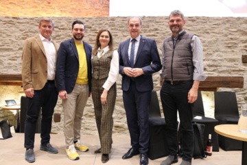 Neun Personen stehen nebeneinander im Granarium der Burg Schlaining. Zu sehen sind Ulrich Elling, Patrick Ratheiser, Karin Tausz, Leonhard Schneemann und Mario Herger. Die Gruppe posiert für ein gemeinsames Foto im Innenraum des historischen Veranstaltungsortes.