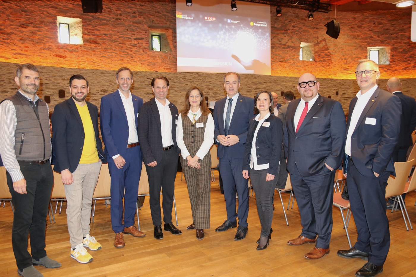 Neun Personen stehen nebeneinander bei einem Symposium im Granarium der Burg Schlaining. Von links nach rechts: Mario Herger, Patrick Ratheiser, Michael Sedlak, Matthias Unger, Karin Tausz, Wirtschaftslandesrat Leonhard Schneemann, Aniko Benkö, Florian Piff, Georg Schönbauer.