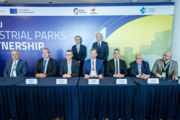 Podiumsdiskussion zu Industrieparks Partnership mit neun Teilnehmern vor blauem Hintergrund mit Berlin Process Logo.