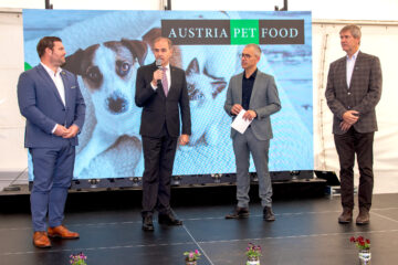Austria Pet Food Pressekonferenz mit vier Geschäftsmännern auf einer Bühne vor großem Display mit Hundemotiven.