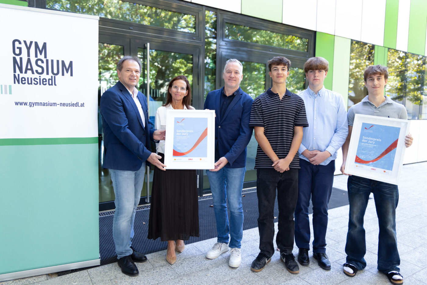 Gymnasium Neusiedl Team mit Preisträgern und Sonderpreis-Urkunden vor Schulgebäude (_r6a8686_innovationspreis_wab)