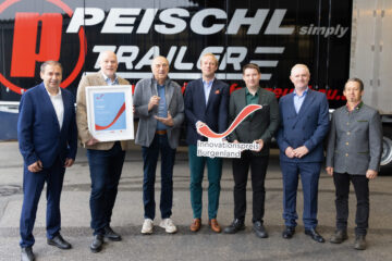 Peischl Trailer gewinnt Innovationspreis Burgenland, sieben Personen halten Auszeichnung und Logo vor Firmengebäude.