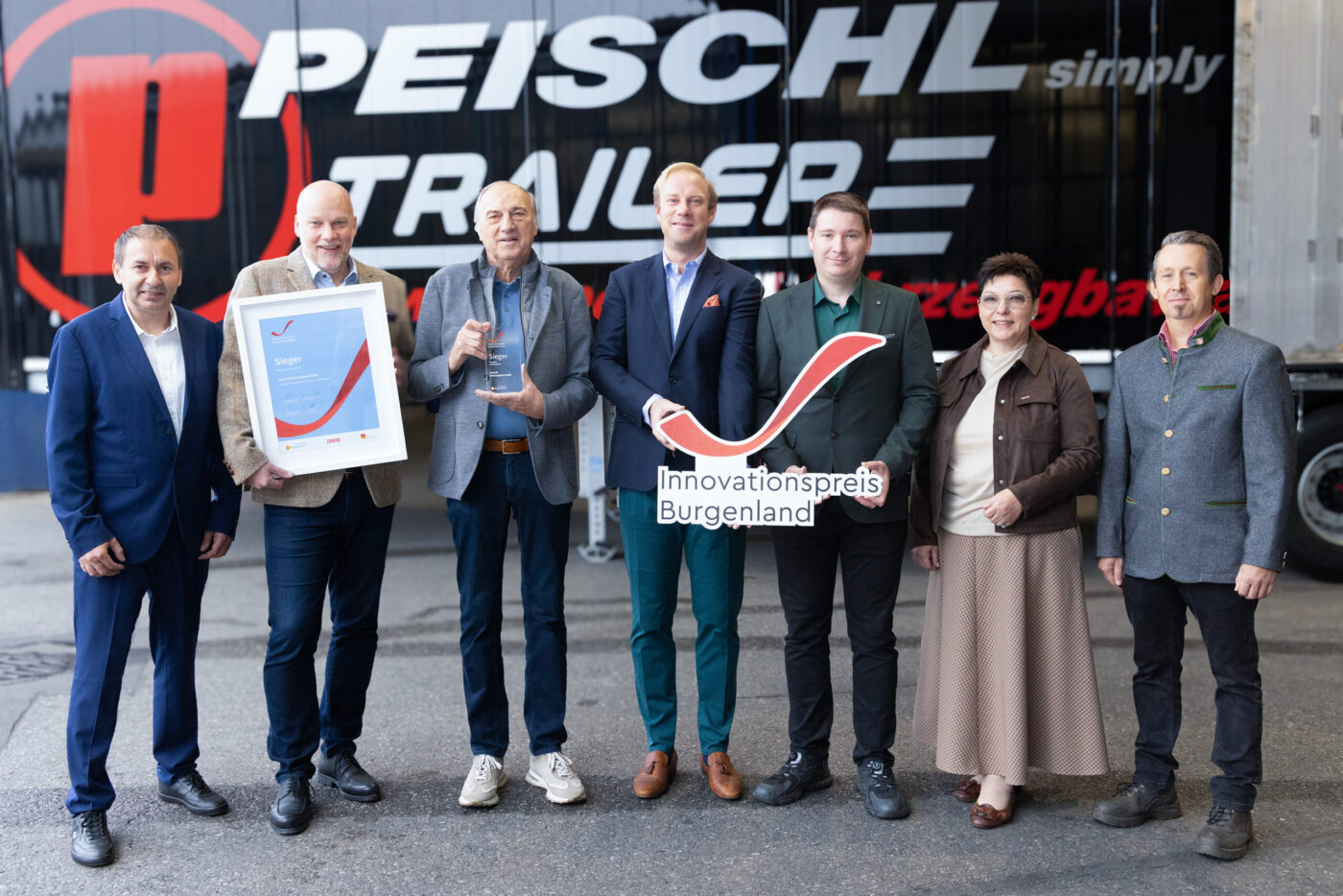 Peischl Trailer Innovationspreis Burgenland - Sieben Personen präsentieren Auszeichnung vor Firmenschild. (_r6a9143_innovationspreis_wab)