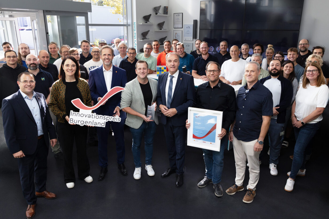 Innovationspreis Burgenland Gewinner mit Team und Urkunde bei Preisverleihung in modernem Büro. (_r6a9353_innovationspreis_wab)